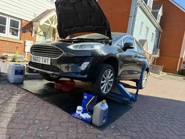 Ford Fiesta on a jack with fresh oil and filters ready for a service on the driveway