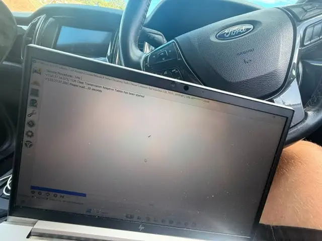 Laptop running diagnostics on a Ford in the driver’s seat